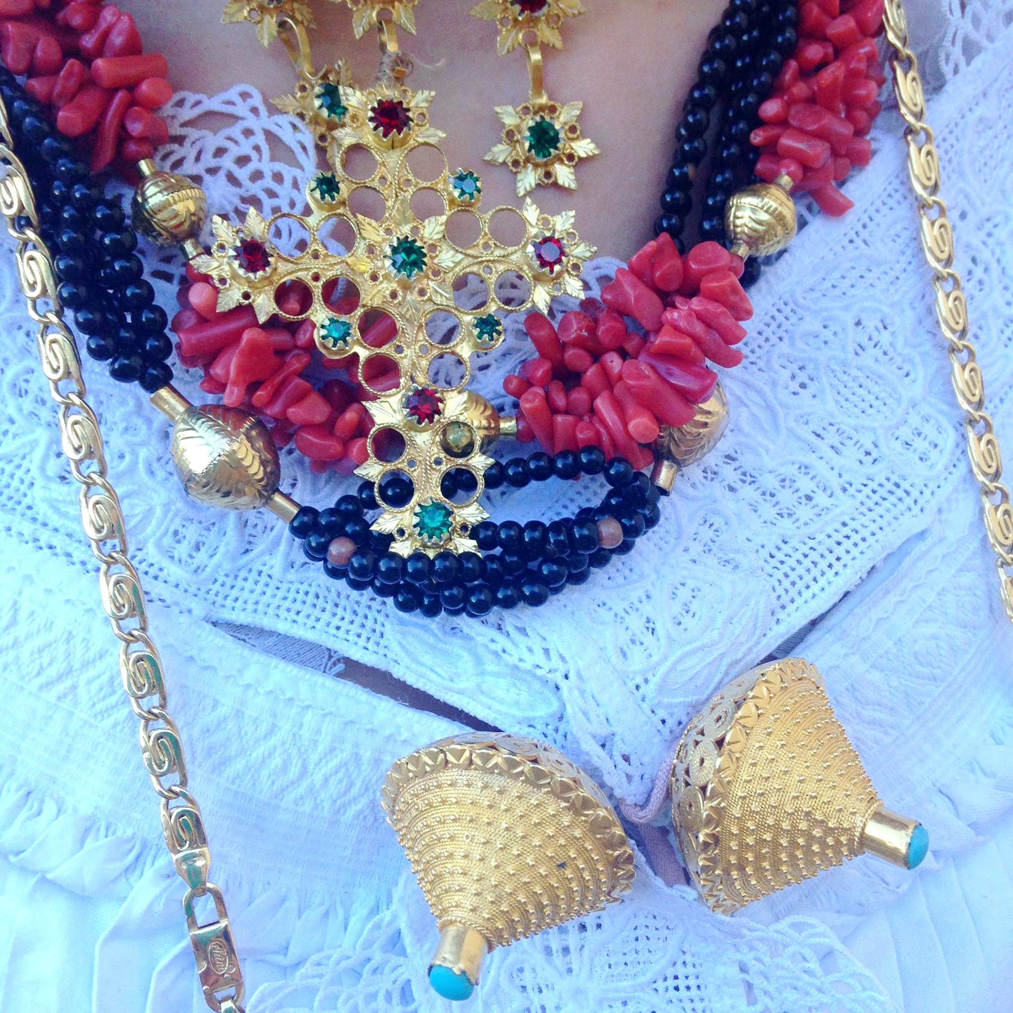 Close-up of layered traditional jewelry featuring gold, red coral, and black beads, worn over a white embroidered garment—perfect inspiration for those seeking unique cultural experiences during international bike tours.