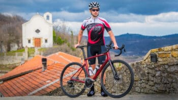 Scenic Italy bike tour with cyclist exploring picturesque village with historic church and rolling hills in the background.