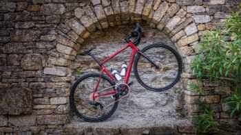 Red road bike mounted on an ancient stone wall in Italy, perfect for exploring scenic cycling tours in Italy and the best bike routes in Europe.