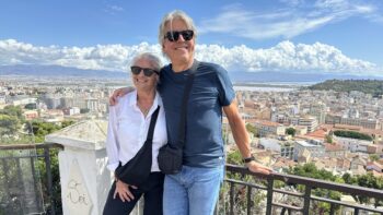 Breathtaking view of a cityscape from a hilltop in Italy with a smiling elderly couple enjoying a bike tour adventure.