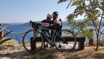 Scenic Italy bike tour with a couple enjoying a lakeside view, perfect for cycling enthusiasts exploring Italy's beautiful landscapes and scenic routes with Ciclismo Classico.