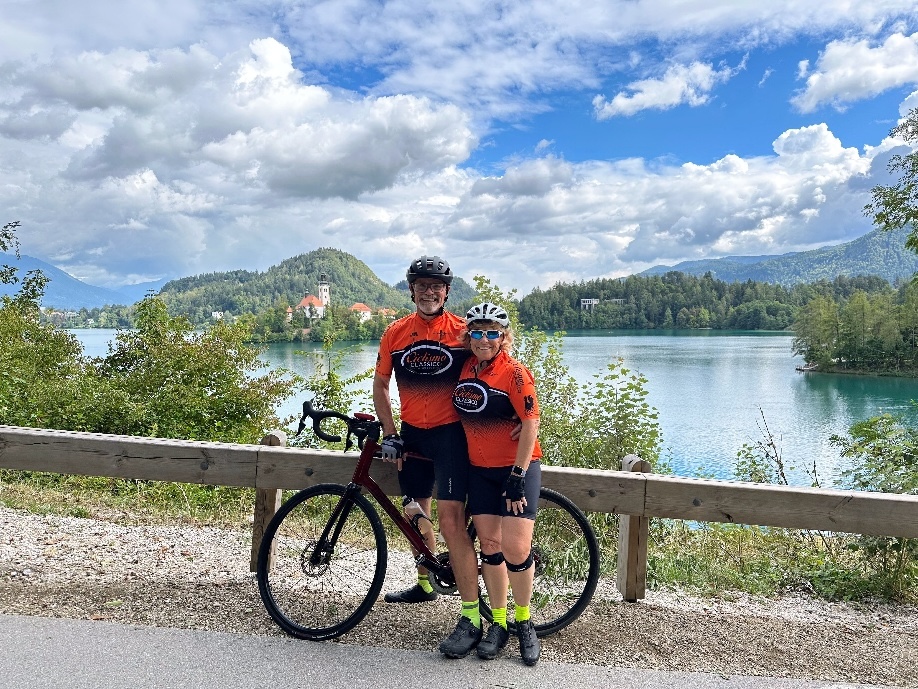 Beautiful Italy bike tour along a serene lake with cyclists in vibrant gear and scenic mountain views.