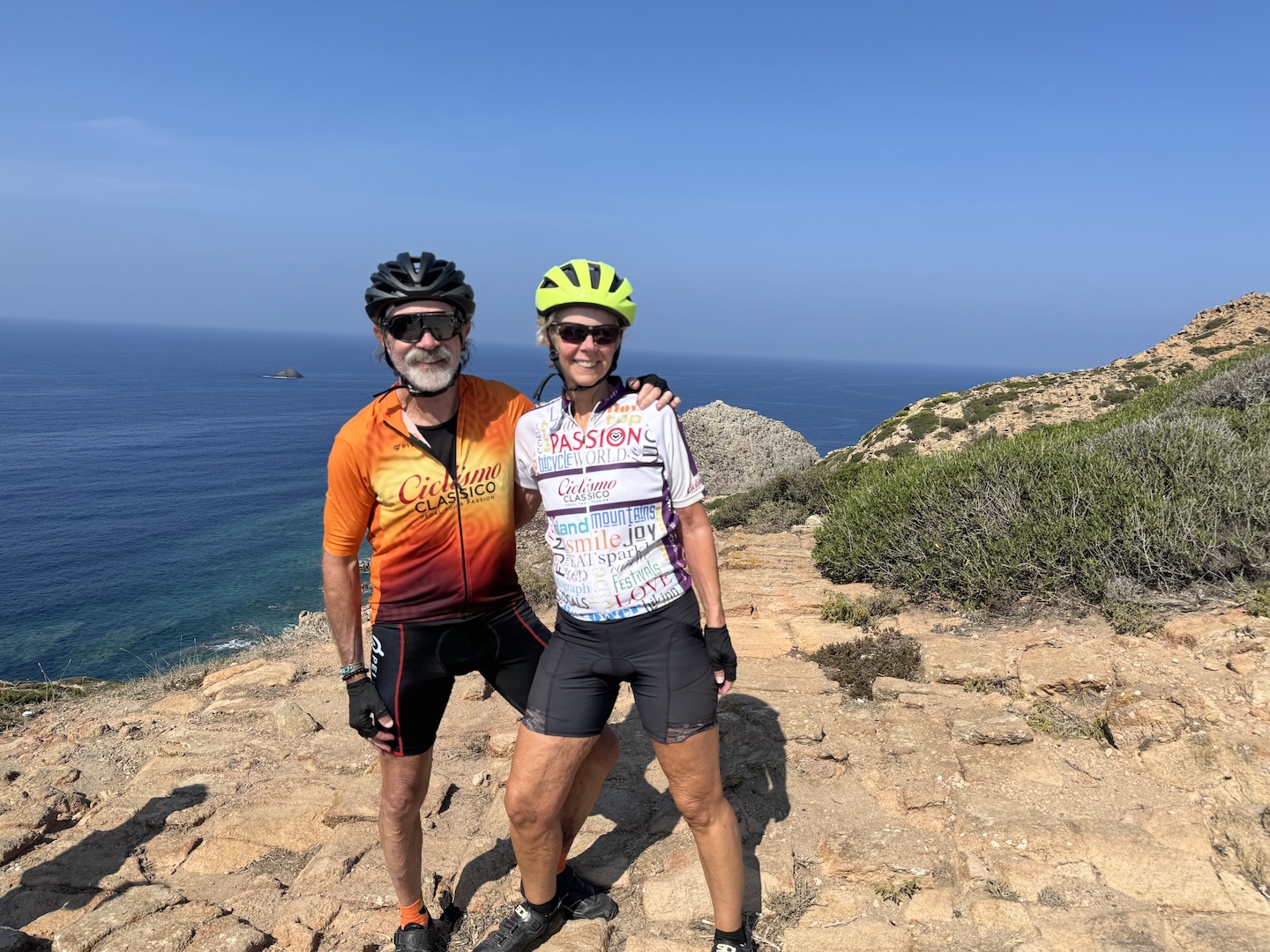 Biking photo of smiling cyclists enjoying a scenic coastal ride along Italy's cliffs with the sea in the background.