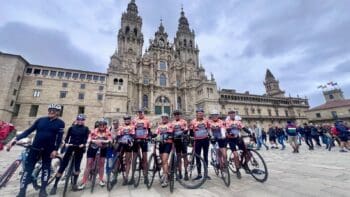 Vibrant group of cyclists in colorful gear posing with bikes in front of a historic Italian cathedral during Italy bike tour, showcasing stunning architecture and scenic cycling routes.