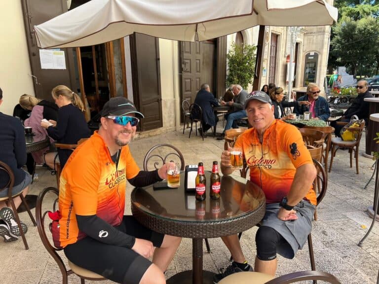 Vibrant Italy bike tour cyclists enjoying drinks at an outdoor café, showcasing scenic bike rides and relaxed stops on an authentic Italian cycling adventure.