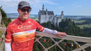 Stylish male cyclist in Italy riding gear with Enchanted Castle of Neuschwanstein in the background.