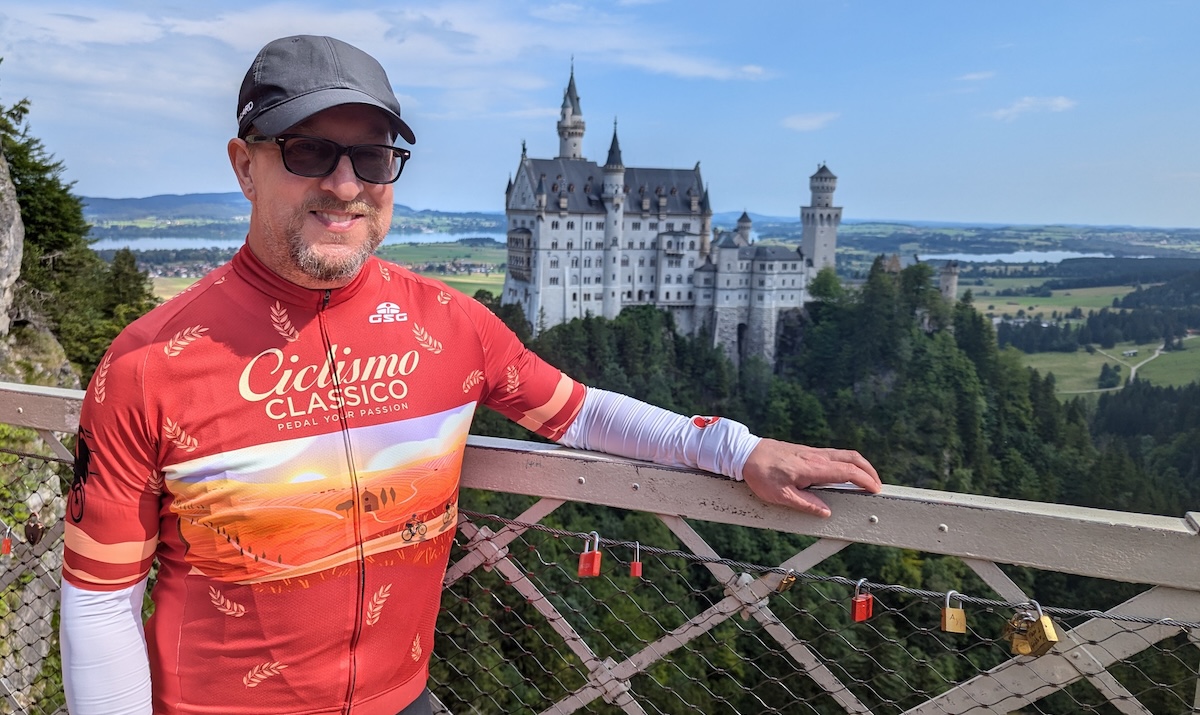Stylish male cyclist in Italy riding gear with Enchanted Castle of Neuschwanstein in the background.