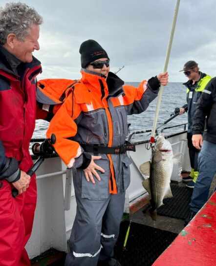 Colorful group of cyclists fishing off a boat on an Italian bike tour adventure in Italy.