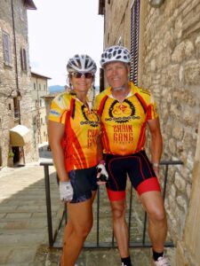 Vibrant Italian cycling duo in bright yellow and red jerseys with scenic historic town backdrop, perfect for Italy bike tours.