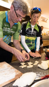 Authentic Italian cooking class with cyclists preparing traditional pasta, showcasing Italy's rich culinary heritage and scenic bike tour experiences.
