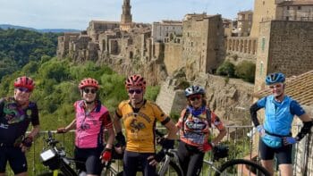 Group of cyclists enjoying a guided bike tour through historic Italian towns with scenic views and ancient architecture, perfect for cycling enthusiasts exploring Italy.