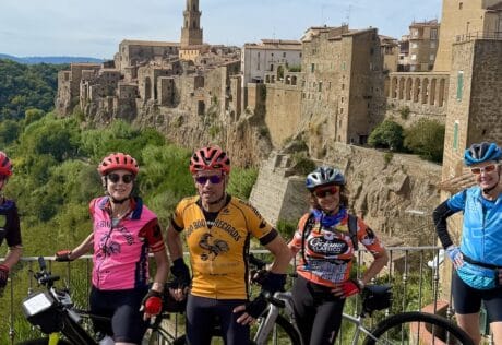 Group of cyclists enjoying a guided bike tour through historic Italian towns with scenic views and ancient architecture, perfect for cycling enthusiasts exploring Italy.